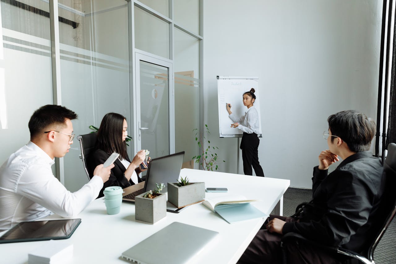 A diverse group discussing business strategies in a modern office setting, using laptops and flipcharts.